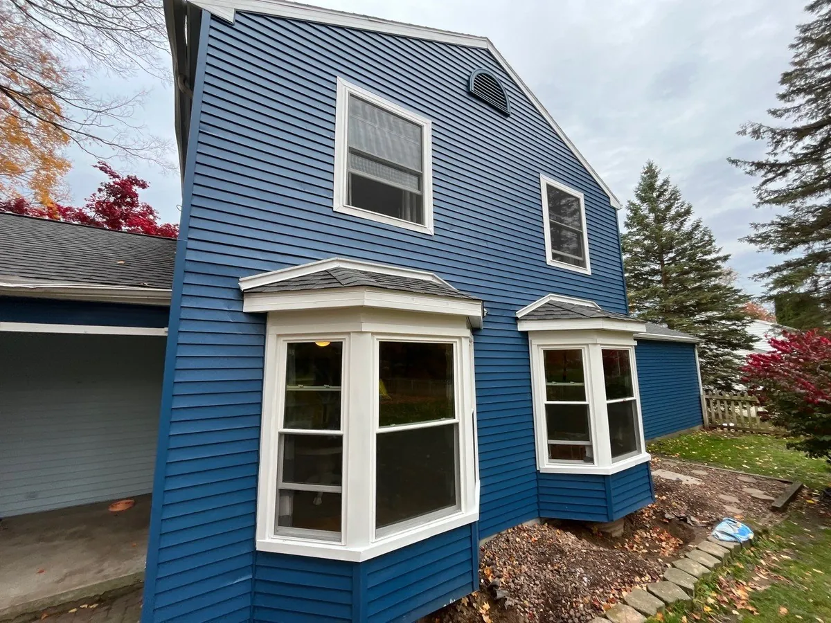 Two-story home with blue siding and twin projecting first-floor white bay windows